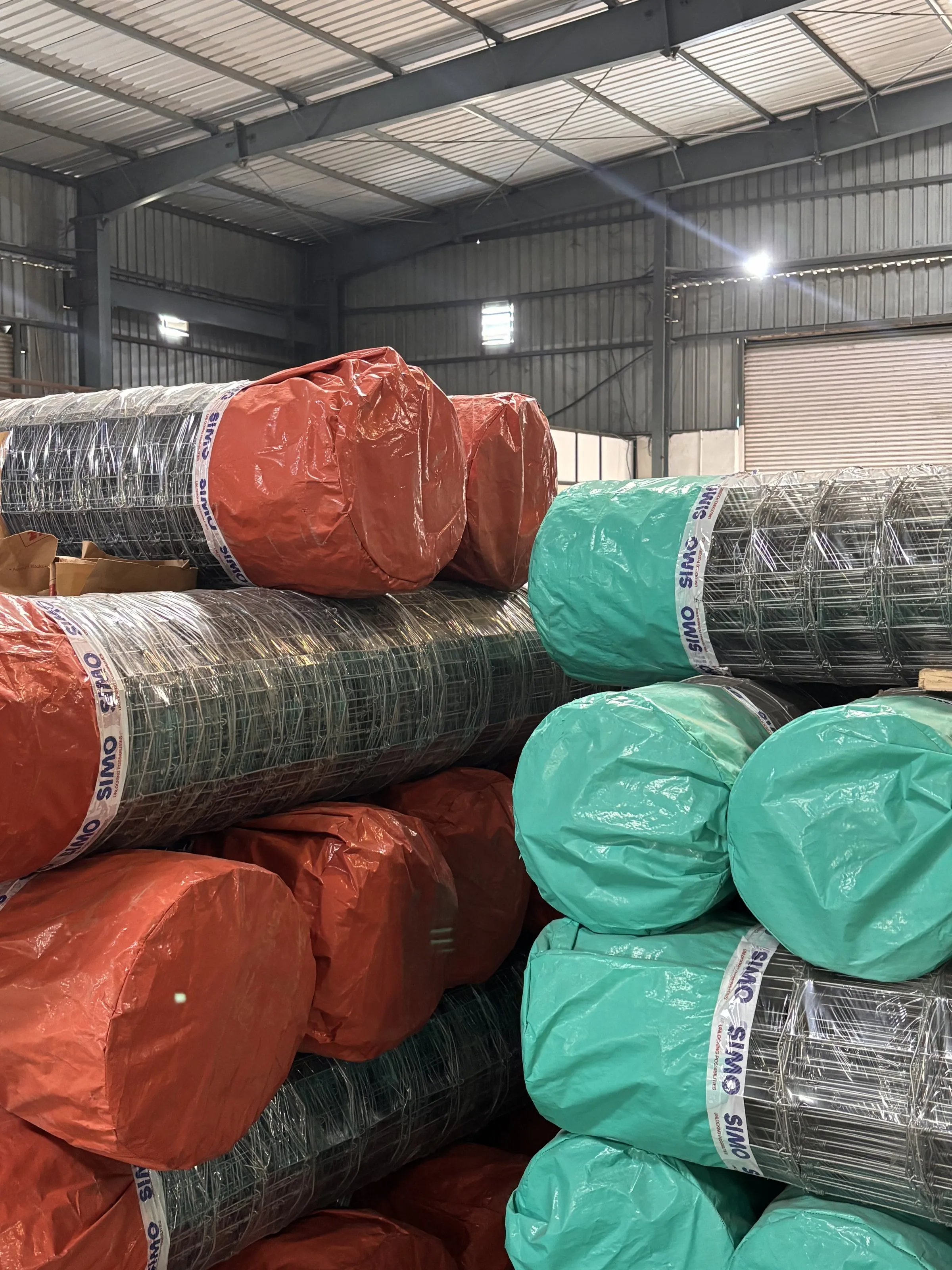 SIMO Securon fence rolls in the warehouse, wrapped in terracotta and teal with SIMO tape
